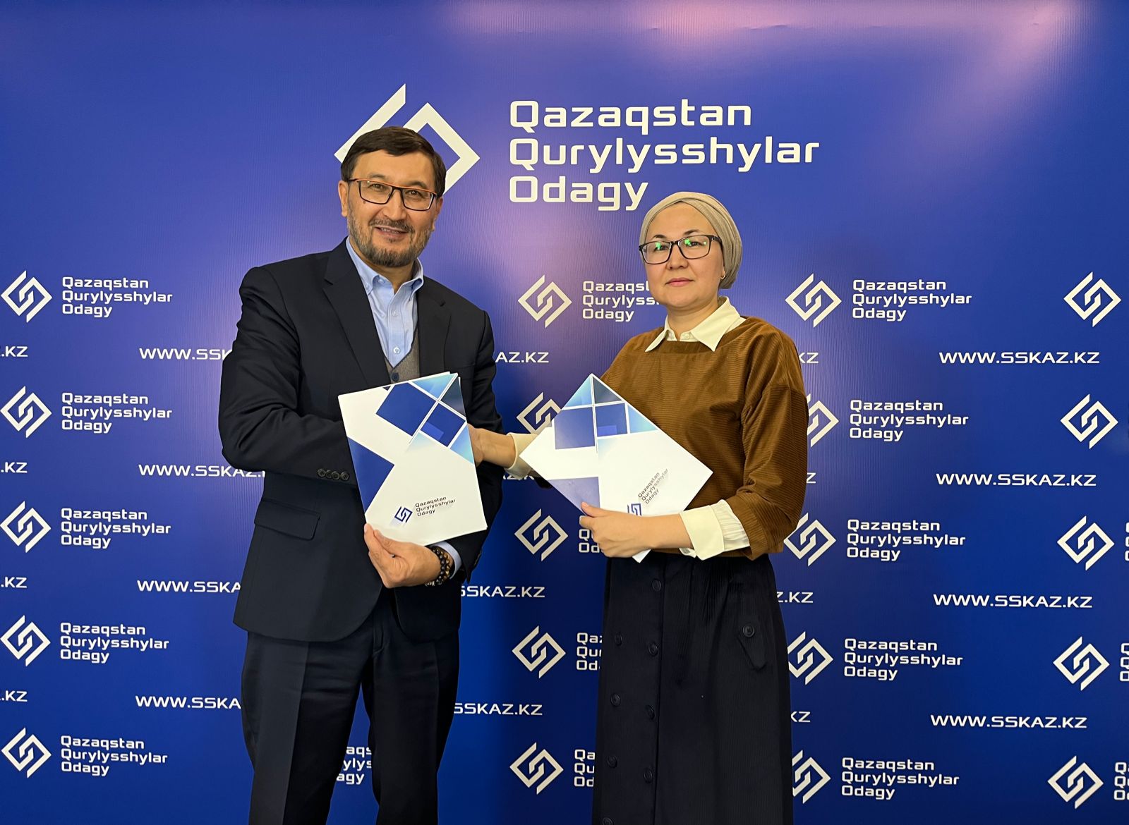 Директор РОЮЛ «Союз строителей Казахстана» и директор «FIABCI-Central Asia» держат в руках подписанный меморандум